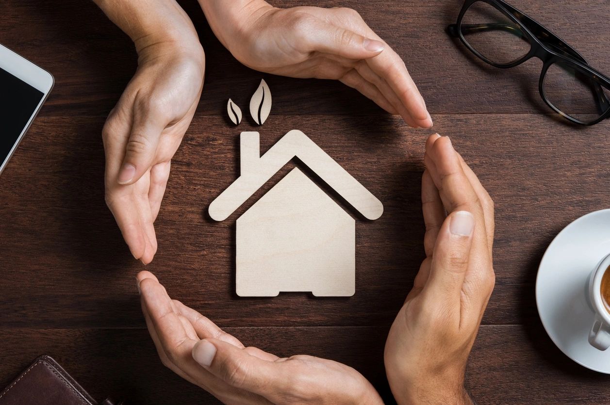 A group of people holding hands around a wooden house.