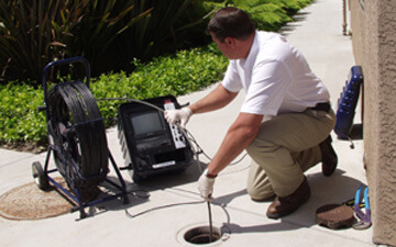 A man is using a tool to check the hole in the ground.